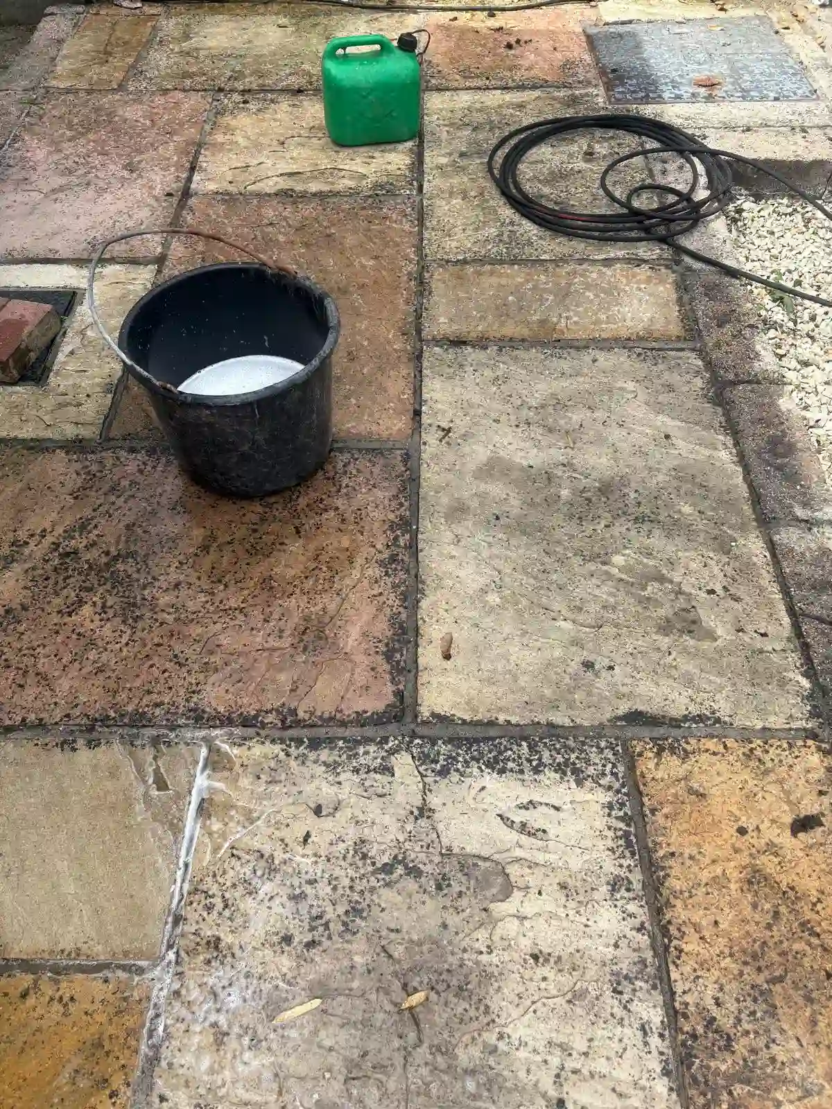 Patio before pressure washing Dublin — black staining and moss on natural stone patio, Reflect General Maintenance