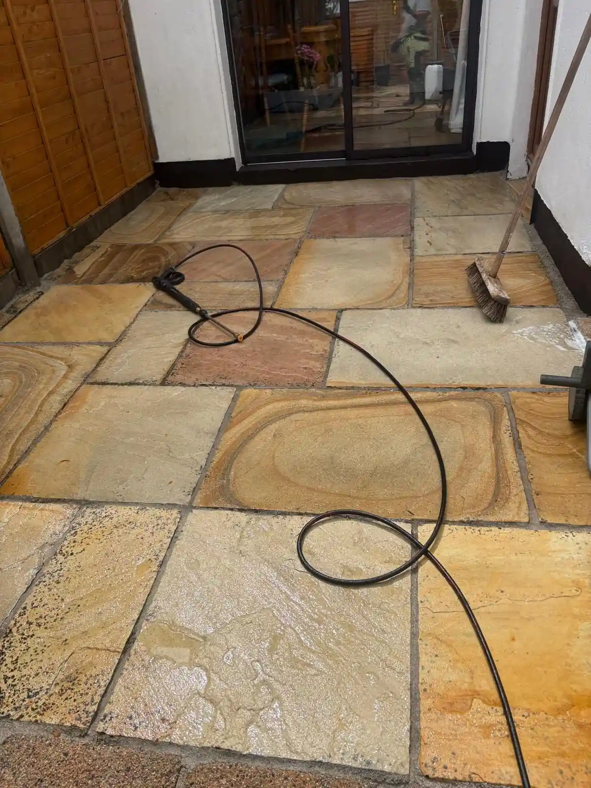 Sandstone patio surface being pressure washed during a Reflect exterior cleaning job