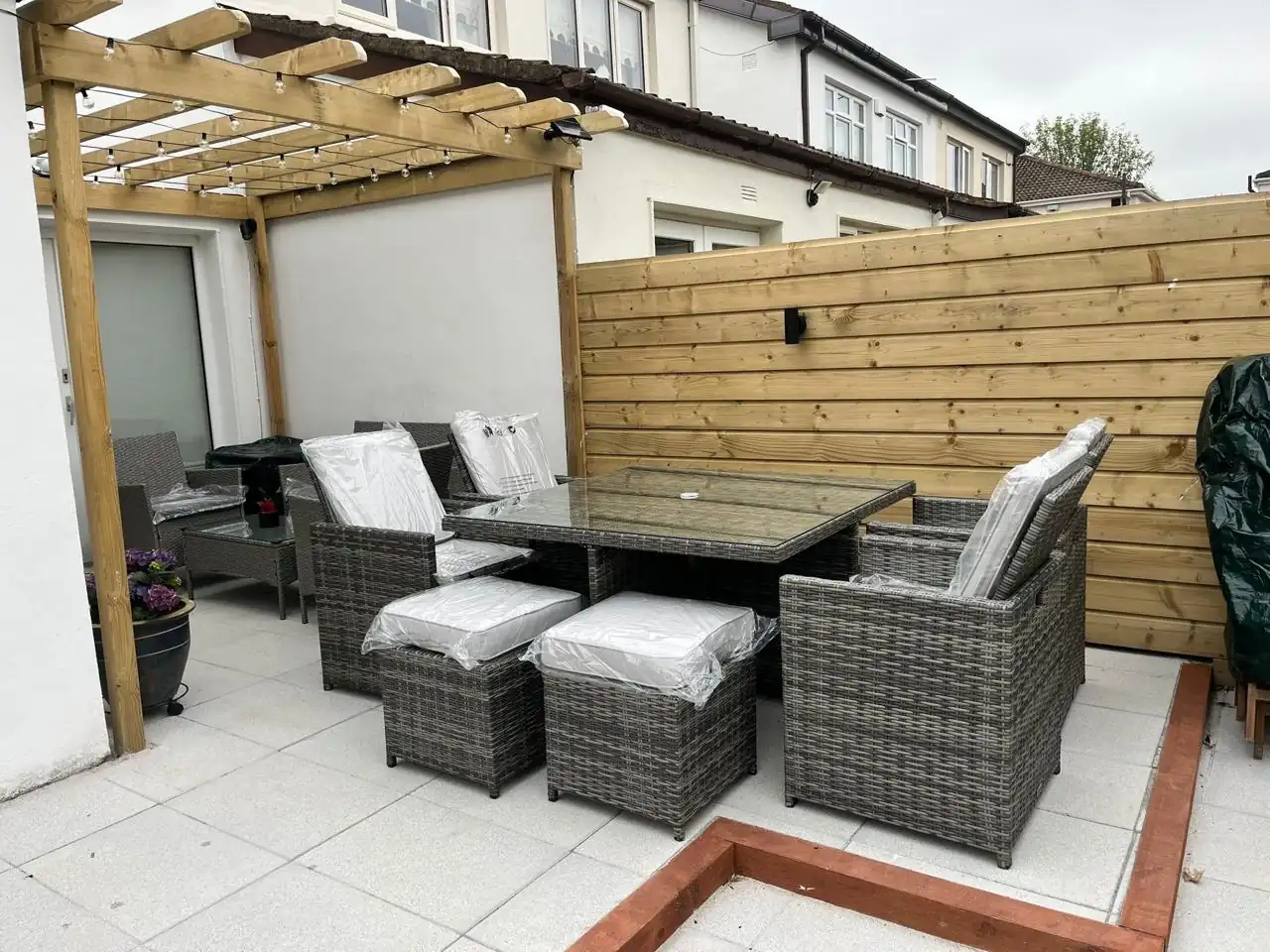 Grey wooden pergola with rattan dining set in a garden seating area
