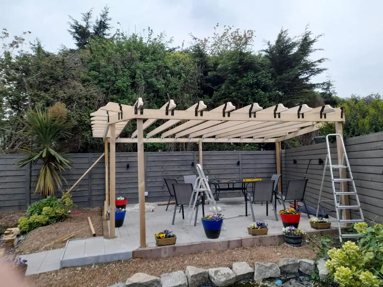 Wooden pergola installation over a garden patio